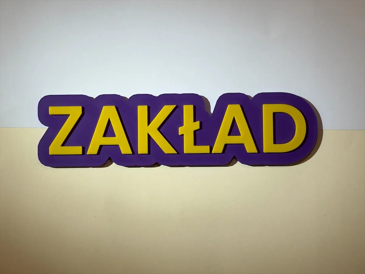 The Napis - napis na drzwi ZAKŁAD, fioletowa baza i żółte litery, na jasnym dwubarwnym tle