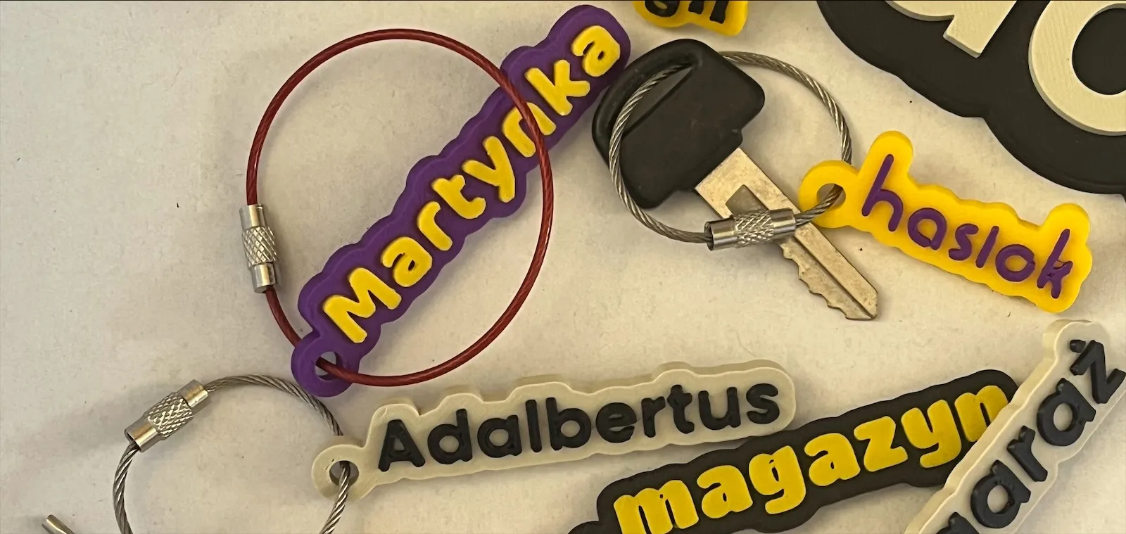 Stół w świetle dziennym: breloczki Martynka, haslok, Adalbertus, magazyn i garaż z linkami stalowymi